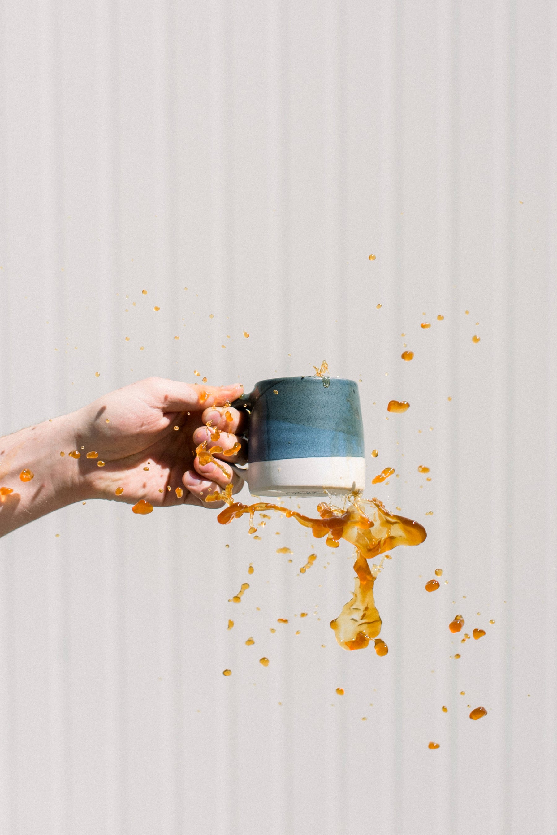 Coffee spilling out of mug against white wall