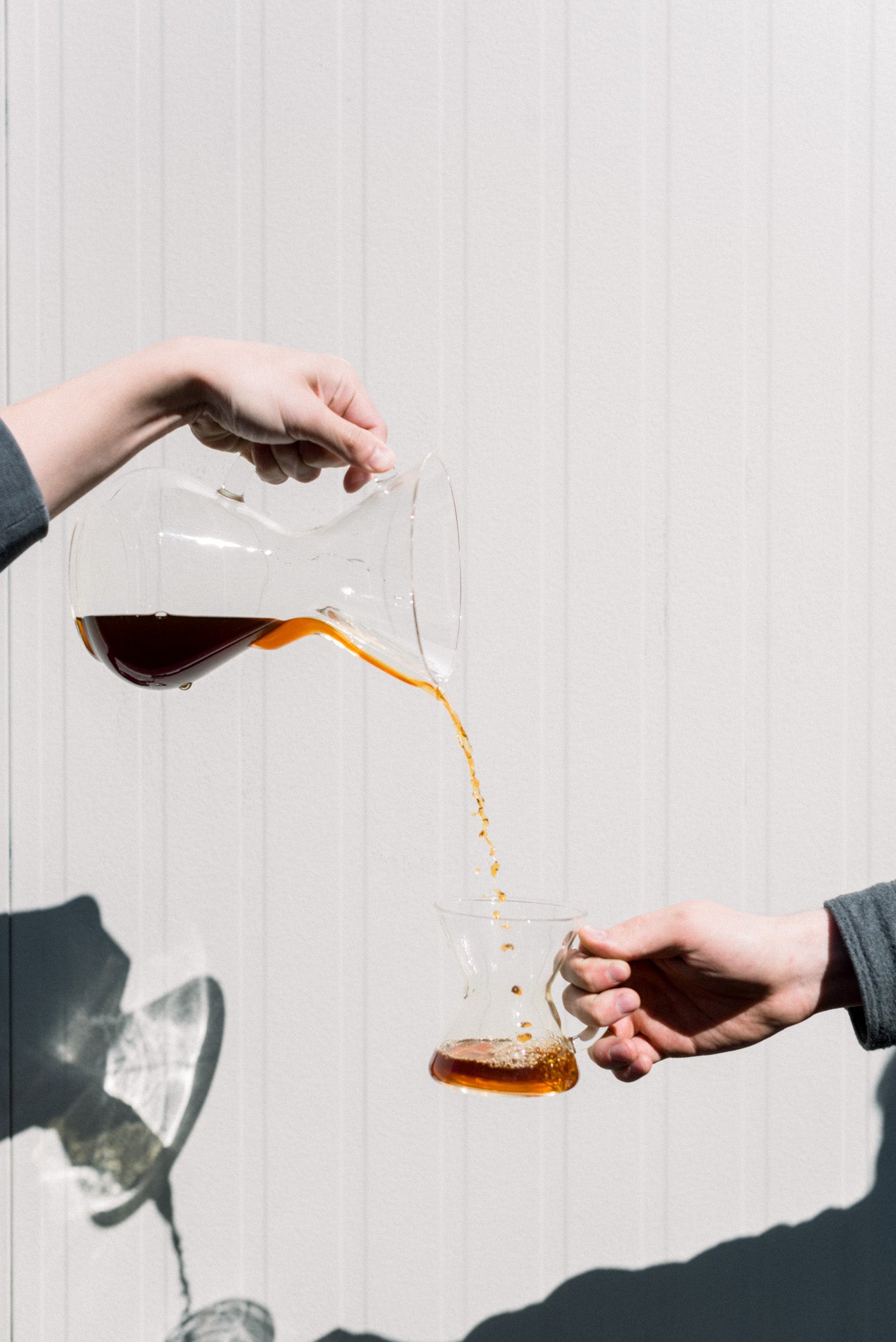Coffee pouring from pitcher into smaller mug